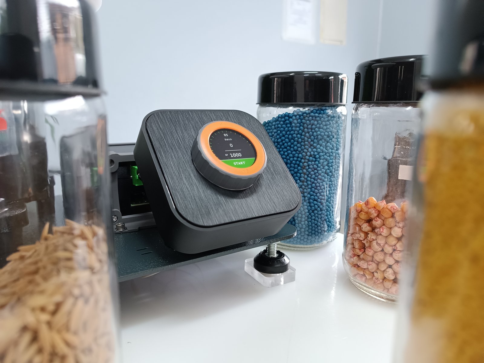 Interface circular do ESC 2025 com display touch e dial, ao lado de frascos de amostras